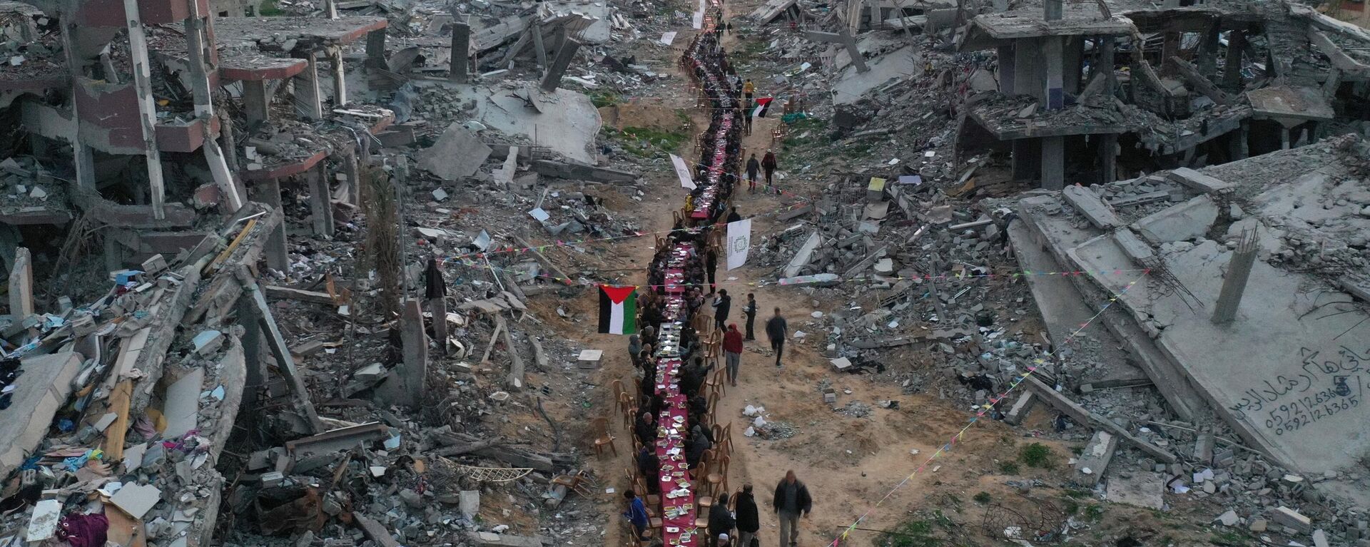 An aerial view of hundreds of Palestinians in the Tel al-Hawa neighbourhood breaking their Iftar at a large table set amidst the rubble in the ruined streets in Gaza City, Gaza on March 09, 2025. - Sputnik Africa, 1920, 10.03.2025