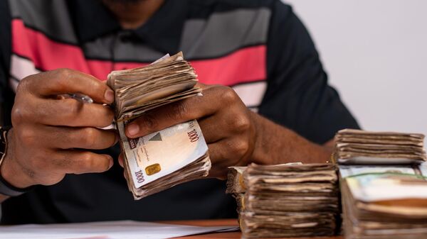 The close-up shot of an african black man counting Nigerian Naira money at his desk - Sputnik Africa