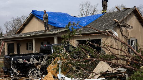 People help cover a damaged roof on March 15, 2025 in Poplar Bluff, Missouri. - Sputnik Africa