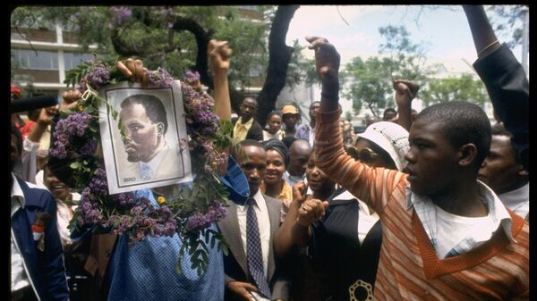 Des manifestants brandissent un portrait du militant sud-africain des droits civiques Steve Biko devant le tribunal de la Vieille Synagogue de Pretoria, où se déroule l'enquête sur sa mort. Biko est décédé alors qu'il était détenu par la police de sécurité sud-africaine. (Photo de Sahm Doherty/Getty Images) - Sputnik Afrique