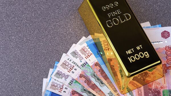 Gold bullion ingot and Russian ruble banknotes. The banknotes are spread out in a fan and pinned down with an ingot of gold. - Sputnik Africa