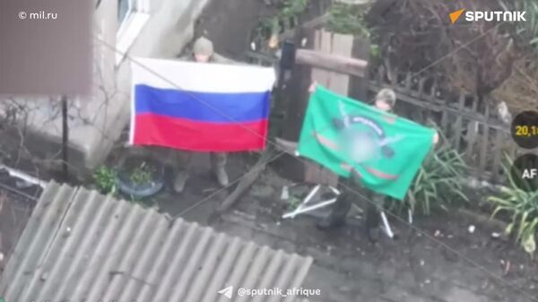 ▶ Des soldats russes tiennent le drapeau tricolore dans une localité récemment libérée dans le Donbass - Sputnik Afrique