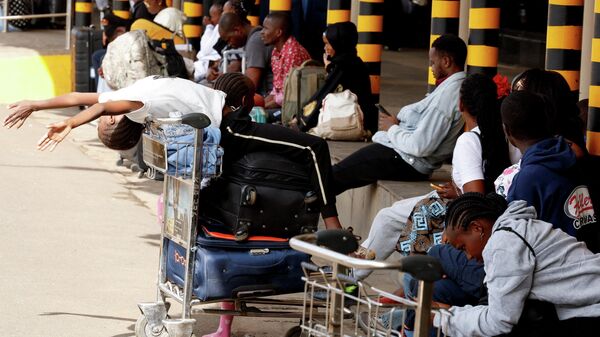 Stranded travellers sit after their flights were delayed due to a strike by workers at the Jomo Kenyatta International Airport (JKIA) in Nairobi, Kenya, February 17, 2026. - Sputnik Africa