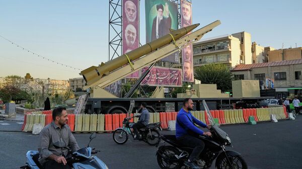 People drive past a domestically-built missile Khaibar-buster, and banners showing portraits of the now-late Iranian Supreme Leader Ayatollah Ali Khamenei, displayed in a military exhibition commemorating the anniversary of the start of the 1980-88 Iraq-Iran war, in Tehran, Sept. 25, 2025.  - Sputnik Africa
