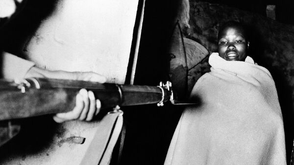 A member of the Mau Mau, wrapped in the blanket in which he was sleeping, is held at gun point during a roundup at 2:30 a.m., by the Fifth Battalion King's African Rifles in the Nyeri district of Kenya on Nov. 13, 1952. - Sputnik Africa