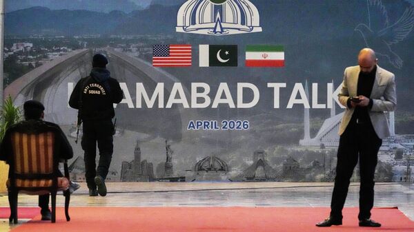 A security guard walks past a billboard  of the U.S. Iran talks outside a media center set up for the coverage of the U.S. Iran official meeting, in Islamabad, Pakistan, April 12, 2026.  - Sputnik Afrique