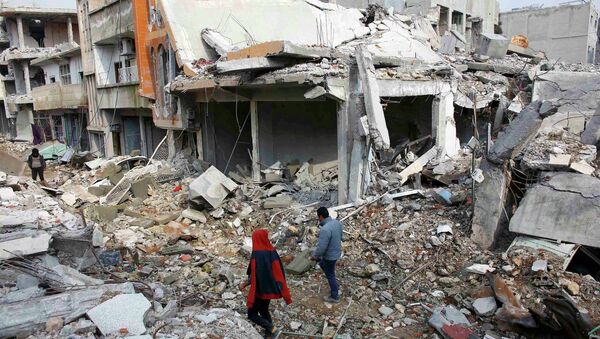 Les gens marchent sur les débris de bâtiments endommagés par l'EI en janvier de la ville syrien du Nord de Kobani - Sputnik Afrique