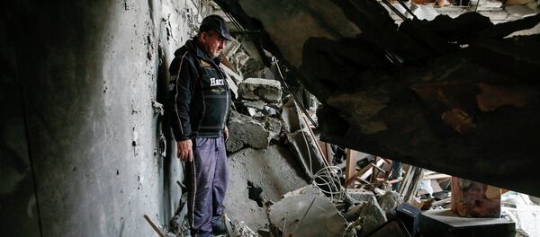 A man looks at the debris inside a flat at a residential block damaged by a recent shelling in Yenakieve town - Sputnik Afrique