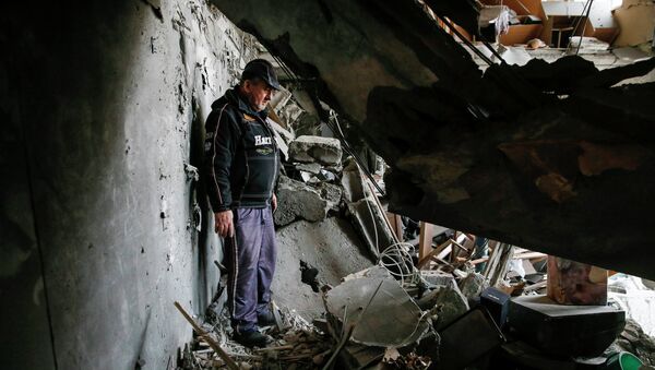 A man looks at the debris inside a flat at a residential block damaged by a recent shelling in Yenakieve town - Sputnik Afrique