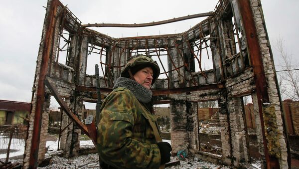 A member of the armed forces of the separatist self-proclaimed Donetsk People's Republic looks on near a building destroyed during battles with the Ukrainian armed forces in Vuhlehirsk, Donetsk region, February 4, 2015 - Sputnik Afrique