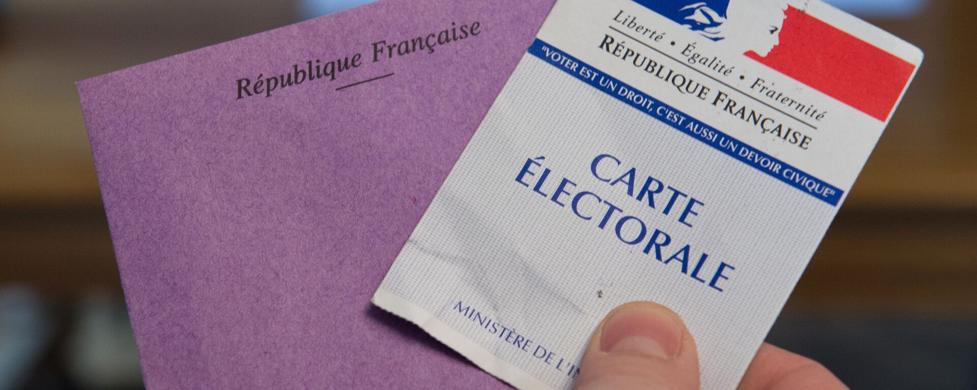 A man holds his electoral card and a ballot as he votes in the second round of the legislative by-election in the 4th constituency of the Doubs in Pont-de-Roide on February 8, 2015.  - Sputnik Afrique, 1920, 17.06.2021