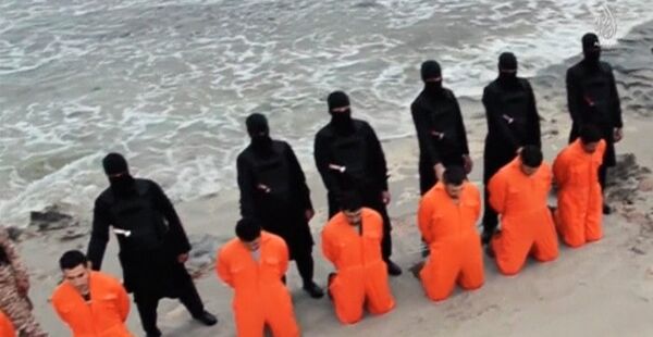 Men in orange jumpsuits purported to be Egyptian Christians held captive by the Islamic State (IS) kneel in front of armed men along a beach said to be near Tripoli, in this still image from an undated video made available on social media on February 15, 2015. - Sputnik Afrique