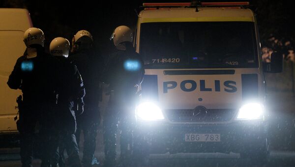 Police force secure the area where firemen extinguish a burning car parking in an indoor garage in the Stockholm suburb of Tureberg after youths rioted in several different suburbs around Stockholm, Sweden for a fourth consecutive night on May 24, 2013. - Sputnik Afrique