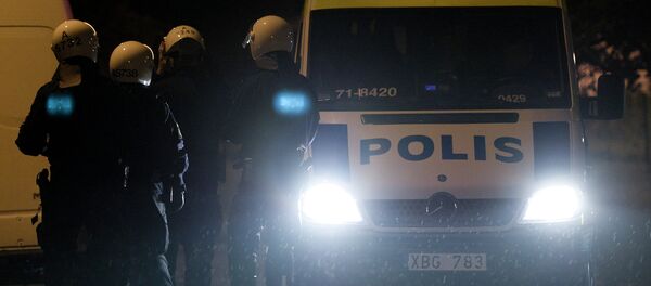 Police force secure the area where firemen extinguish a burning car parking in an indoor garage in the Stockholm suburb of Tureberg after youths rioted in several different suburbs around Stockholm, Sweden for a fourth consecutive night on May 24, 2013. - Sputnik Afrique