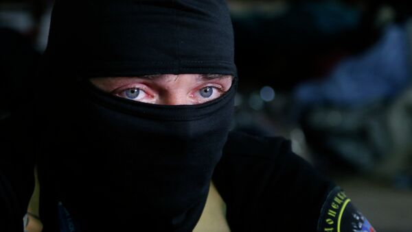 A masked pro-Russian activist guard looks through a window of the regional administration building seized earlier in Donetsk, Ukraine, Friday, April 18, 2014 - Sputnik Afrique