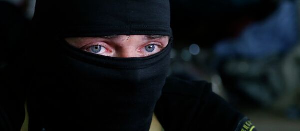 A masked pro-Russian activist guard looks through a window of the regional administration building seized earlier in Donetsk, Ukraine, Friday, April 18, 2014 - Sputnik Afrique