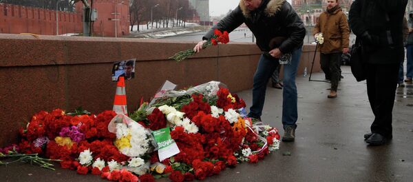 People come to lay flowers at the site, where Boris Nemtsov was shot dead, with St. Basil's Cathedral (R) and the Kremlin walls seen in the background, in central Moscow, February 28, 2015. - Sputnik Afrique