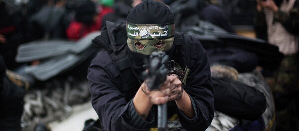 A Palestinian Hamas masked gunman shows his military skills during a rally to commemorate the 27th anniversary of the Hamas militant group, in Gaza City, Sunday, Dec. 14, 2014 - Sputnik Afrique