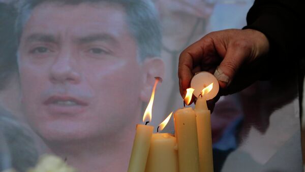 People light candles in memory of Boris Nemtsov, seen behind, at the monument of political prisoners 'Solovetsky Stone' in central St.Petersburg, Russia, Saturday, Feb. 28, 2015. - Sputnik Afrique