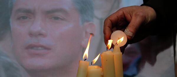 People light candles in memory of Boris Nemtsov, seen behind, at the monument of political prisoners 'Solovetsky Stone' in central St.Petersburg, Russia, Saturday, Feb. 28, 2015. - Sputnik Afrique