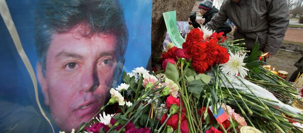 People lay flowers in memory of Boris Nemtsov, seen at left, at the monument of political prisoners 'Solovetsky Stone' in central St. Petersburg, Russia, Saturday, Feb. 28, 2015. - Sputnik Afrique