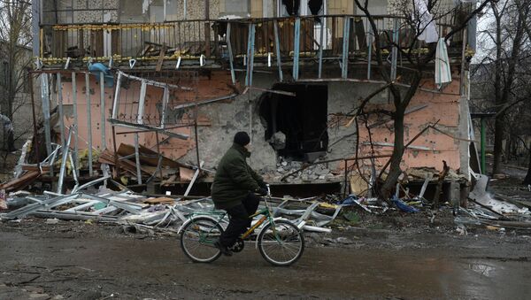 Житель города Дебальцево едет на велосипеде мимо разрушенного в результате обстрелов во время боевых действий жилого дома. - Sputnik Afrique