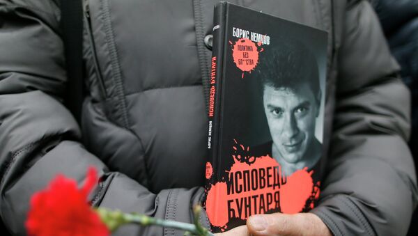 A visitor holds flowers and a book Confessions of the Rebel by Russian leading opposition figure Boris Nemtsov while waiting to attend a memorial service before the funeral of Nemtsov in Moscow, March 3, 2015. - Sputnik Afrique