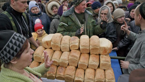 A man speaks to a crowd of residents warning them not to push as they wait to get bread, one per person, baked by Russia-backed separatists in Chornukhyne, Ukraine, Monday, March 2, 2015 - Sputnik Afrique