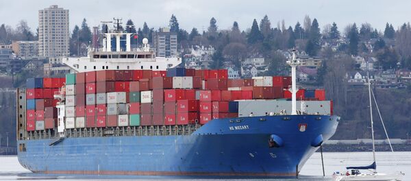 A sailboat moves past the 925-foot long HS Mozart cargo ship in Tacoma, Wash. File photo - Sputnik Afrique