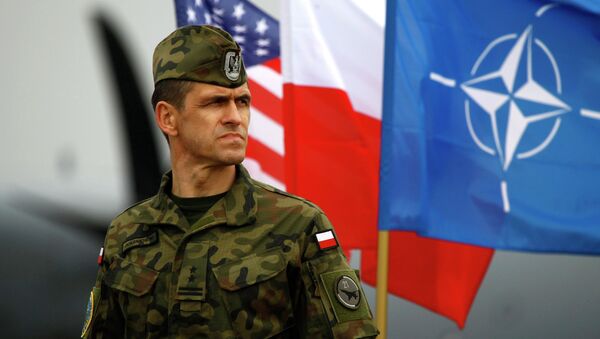 A Polish soldier stands near US and Poland's national flags and a NATO flag in Swidwin, northern west Poland, April 23, 2014 - Sputnik Afrique