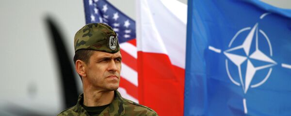 A Polish soldier stands near US and Poland's national flags and a NATO flag in Swidwin, northern west Poland, April 23, 2014 - Sputnik Afrique