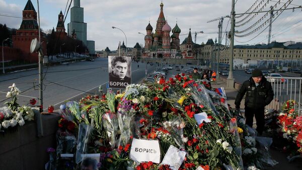 A man walks past flowers at the site where Kremlin critic Boris Nemtsov was murdered on February 27, at the Great Moskvoretsky Bridge, with St. Basil's Cathedral seen in the background, in central Moscow March 6, 2015. - Sputnik Afrique