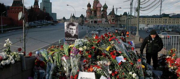 A man walks past flowers at the site where Kremlin critic Boris Nemtsov was murdered on February 27, at the Great Moskvoretsky Bridge, with St. Basil's Cathedral seen in the background, in central Moscow March 6, 2015. - Sputnik Afrique