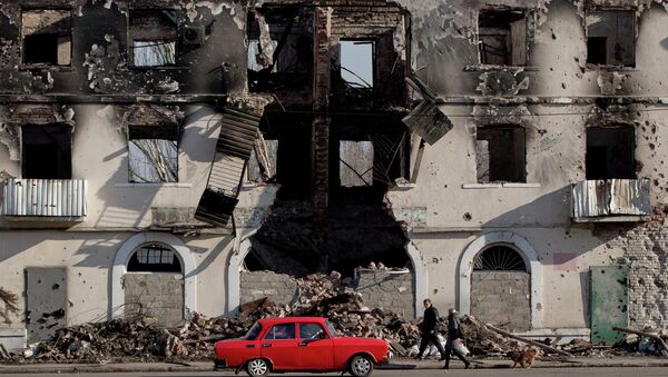 People pass by a destroyed building in Vuhlehirsk, Ukraine, Monday, March 9, 2015 - Sputnik Afrique