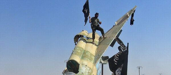 Ffighters of the Islamic State wave the group's flag from a damaged display of a government fighter jet following the battle for the Tabqa air base, in Raqqa, Syria - Sputnik Afrique