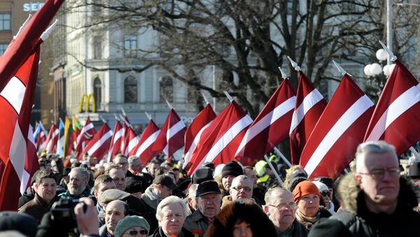 People carry Latvian flags at the march in Riga, Latvia - Sputnik Afrique