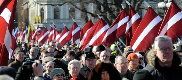 People carry Latvian flags at the march in Riga, Latvia - Sputnik Afrique