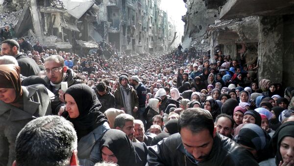 Residents of the besieged Palestinian camp of Yarmouk, queuing to receive food supplies, in Damascus, Syria. - Sputnik Afrique