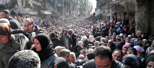 Residents of the besieged Palestinian camp of Yarmouk, queuing to receive food supplies, in Damascus, Syria. - Sputnik Afrique