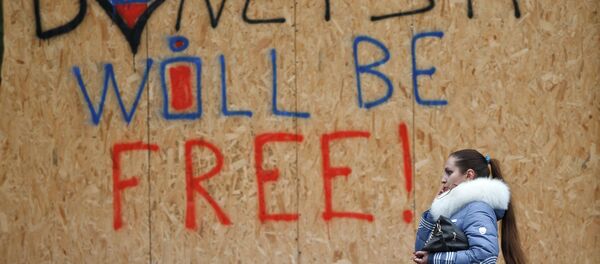 A woman walks by shop windows protected from possible shelling with wooden boards with the inscription Donetsk will be free in Donetsk, Ukraine, Sunday, March 1, 2015 - Sputnik Afrique