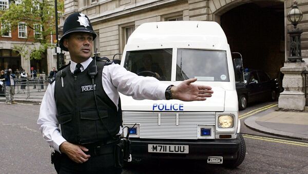 A policeman stops traffic as an armoured policevan leaves Bow street magistrates court in central London - Sputnik Afrique