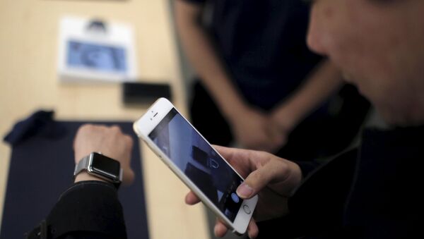 Un client prend une photo d'une montre Apple avec son téléphone portable après dans un Apple Store au centre-ville de Shanghai, le 10 avril 2015 - Sputnik Afrique