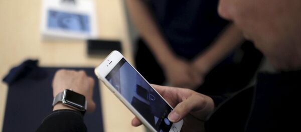 Un client prend une photo d'une montre Apple avec son téléphone portable après dans un Apple Store au centre-ville de Shanghai, le 10 avril 2015 - Sputnik Afrique