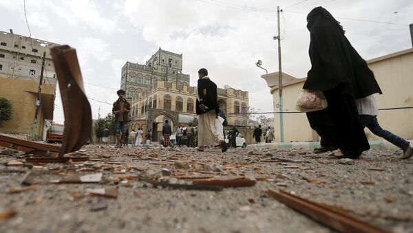 People walk at the site of an air strike in Sanaa April 8, 2015. - Sputnik Afrique