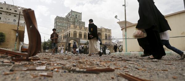 People walk at the site of an air strike in Sanaa April 8, 2015. - Sputnik Afrique
