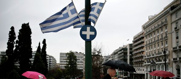 People holding umbrellas make their way next to fluttering Greek national flags on the main Constitution (Syntagma) square during heavy rainfall in Athens - Sputnik Afrique
