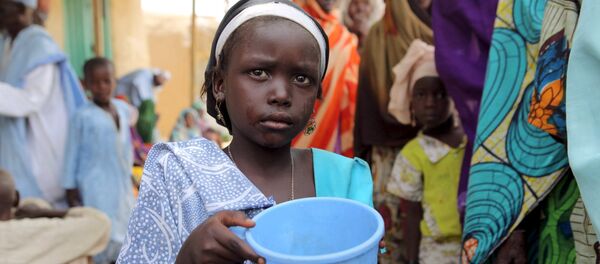 A girl drinks water as women queue for blankets and food given out by Nigerien soldiers in Damasak - Sputnik Afrique