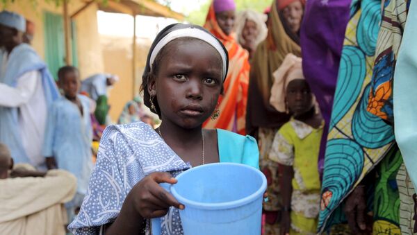 A girl drinks water as women queue for blankets and food given out by Nigerien soldiers in Damasak - Sputnik Afrique