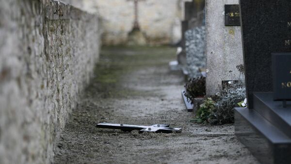picture taken on February 18, 2015 shows a crucifix lying on the ground next to graves at a cemetery in Tracy-sur-Mer, on the coast of Normandy. Dozens of graves have been defaced in the cemetery, the interior minister said on February 17, 2015 - Sputnik Afrique
