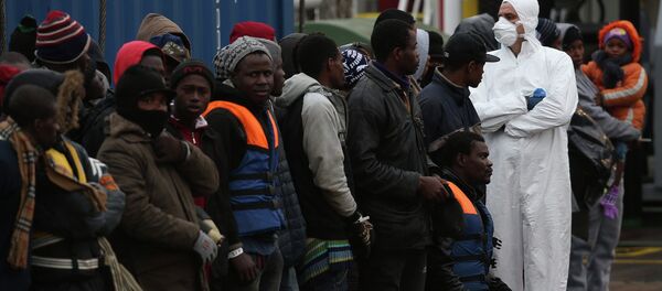 A rescue worker (R) checks migrants as they arrive on the boat Nos Taurus Genova at the Sicilian harbor of Pozzallo, February 16, 2015. - Sputnik Afrique